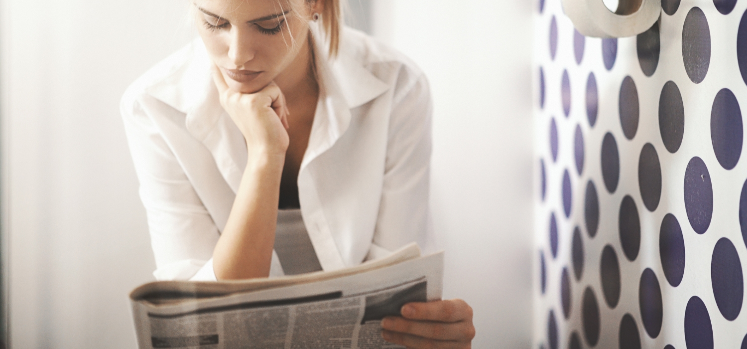 woman reading newspaper on toilet