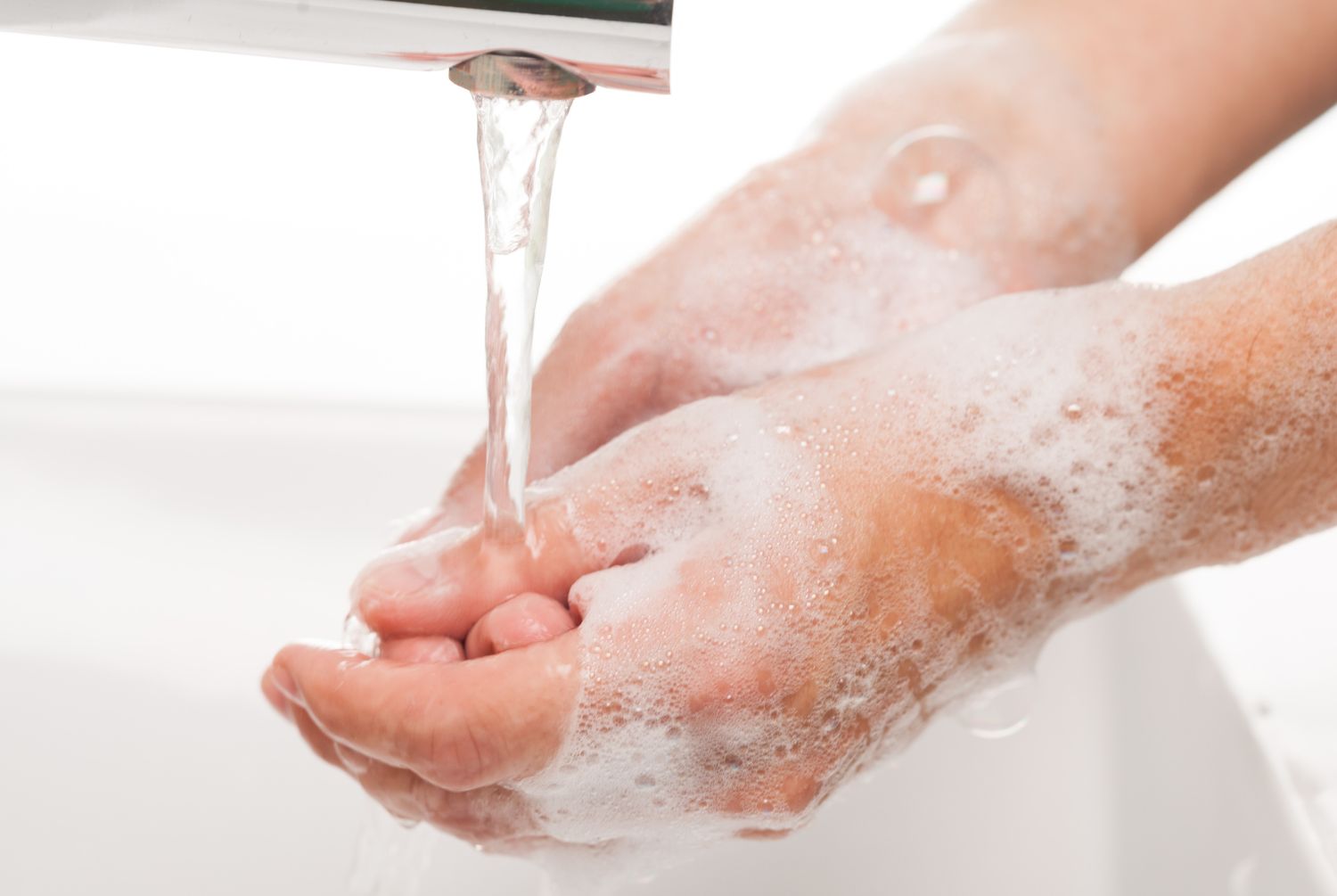 image of person washing hands in water with lots of soap suds
