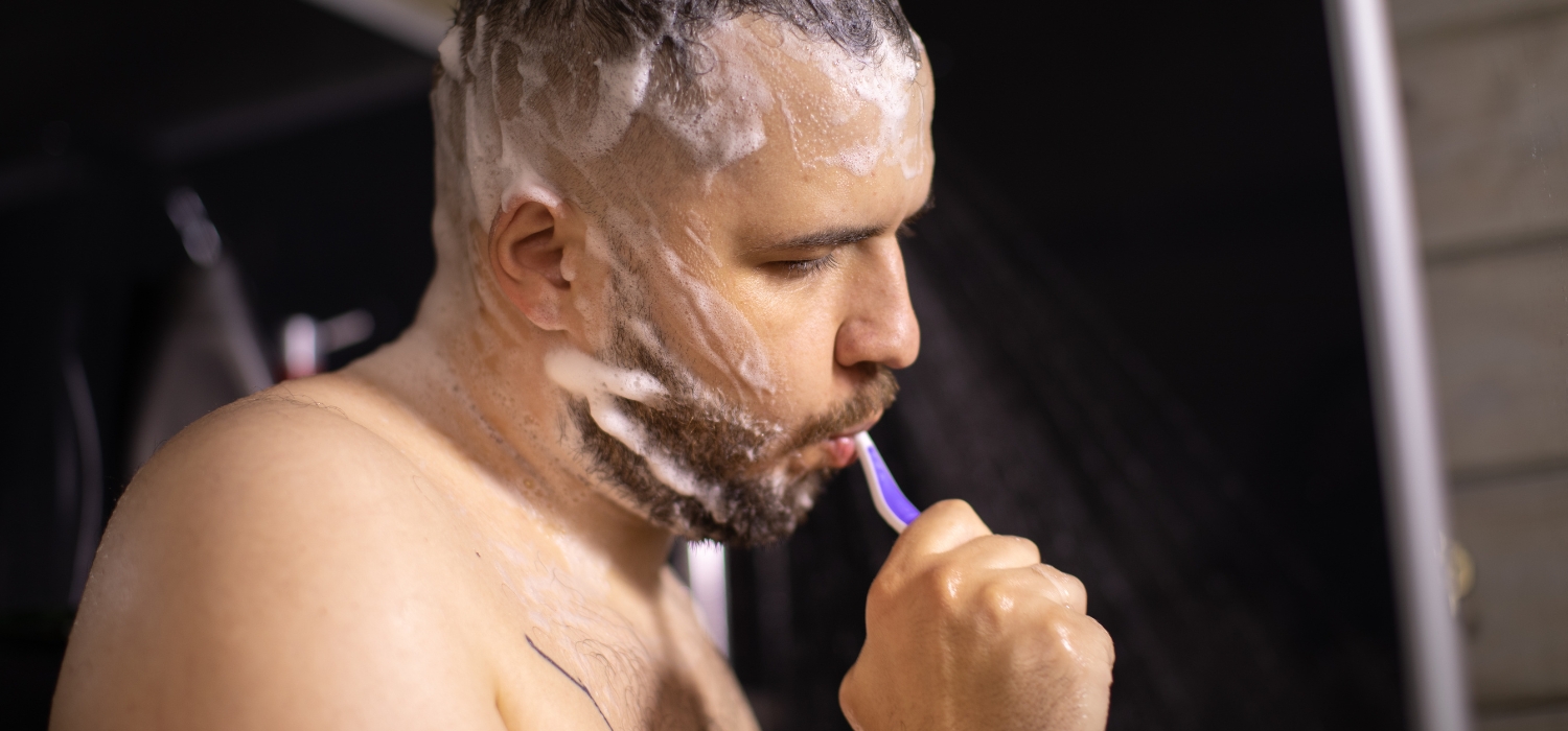 man brushing teeth in shower