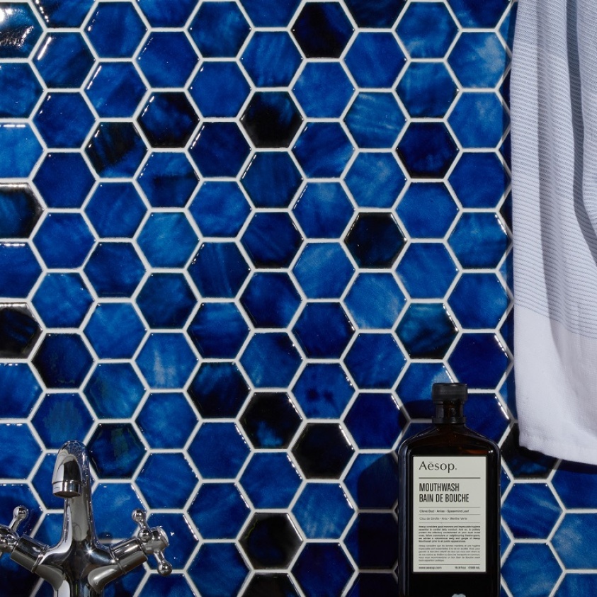 Product lifestyle image of Ca' Pietra Akazu Porcelain Cobalt Blue Mosaic Hexagonal Tiles with bottle and edge of curtain CP0820